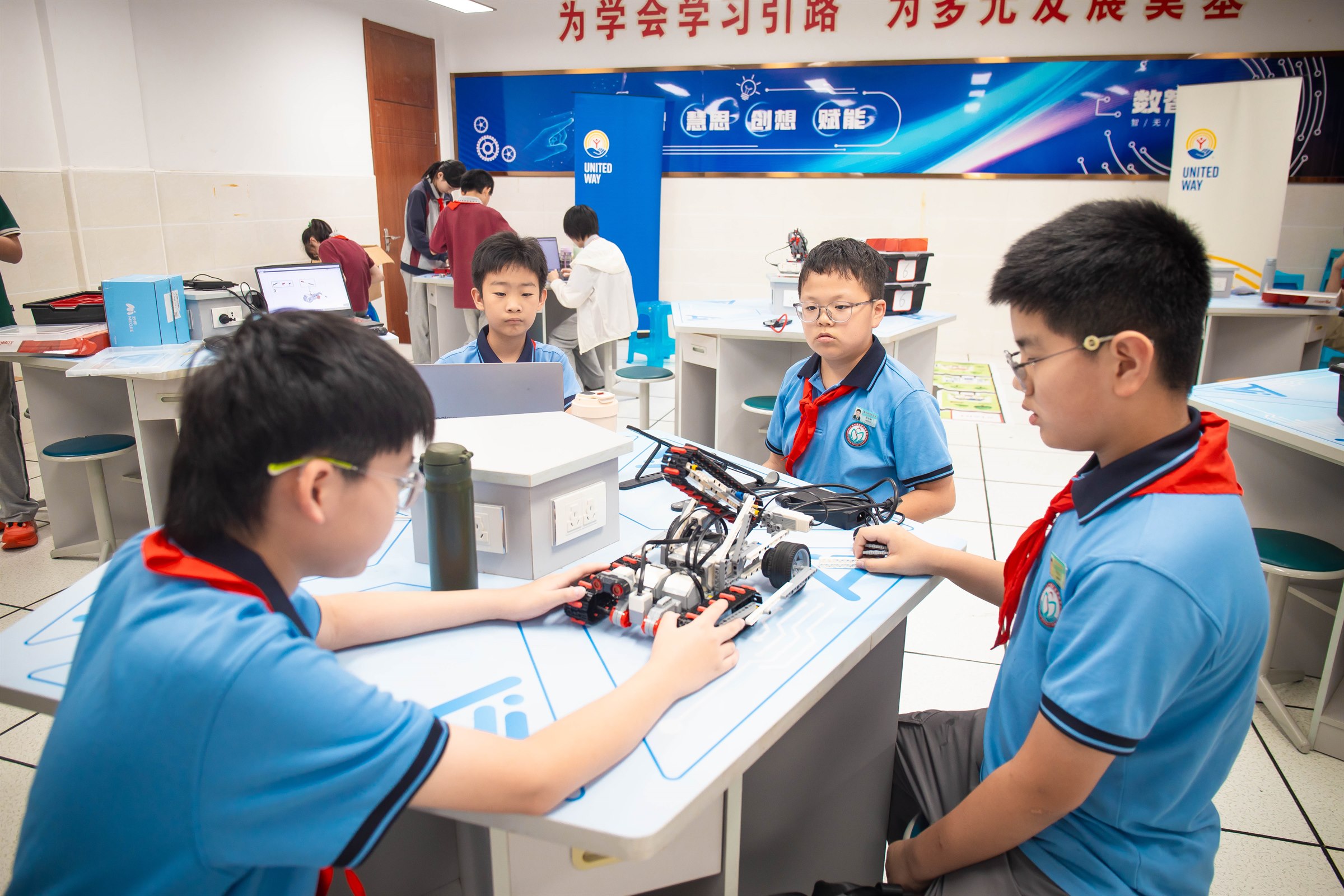 Students work around a wheeled engineering model on a classroom table.